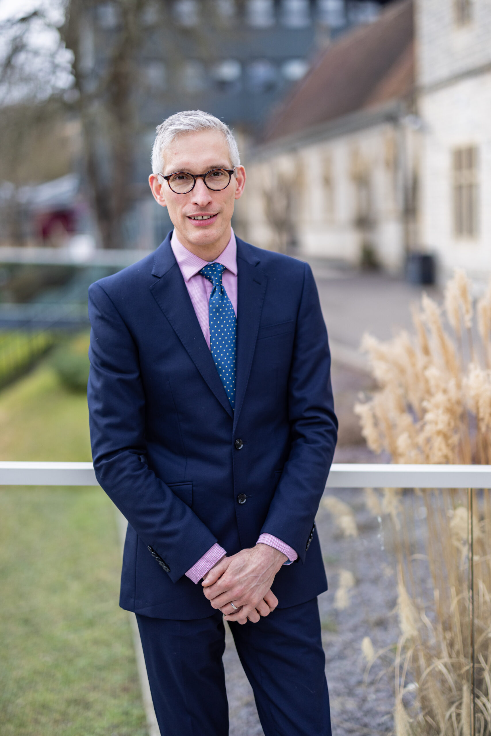 Photo of Philip Dent in suit in front of university buildings