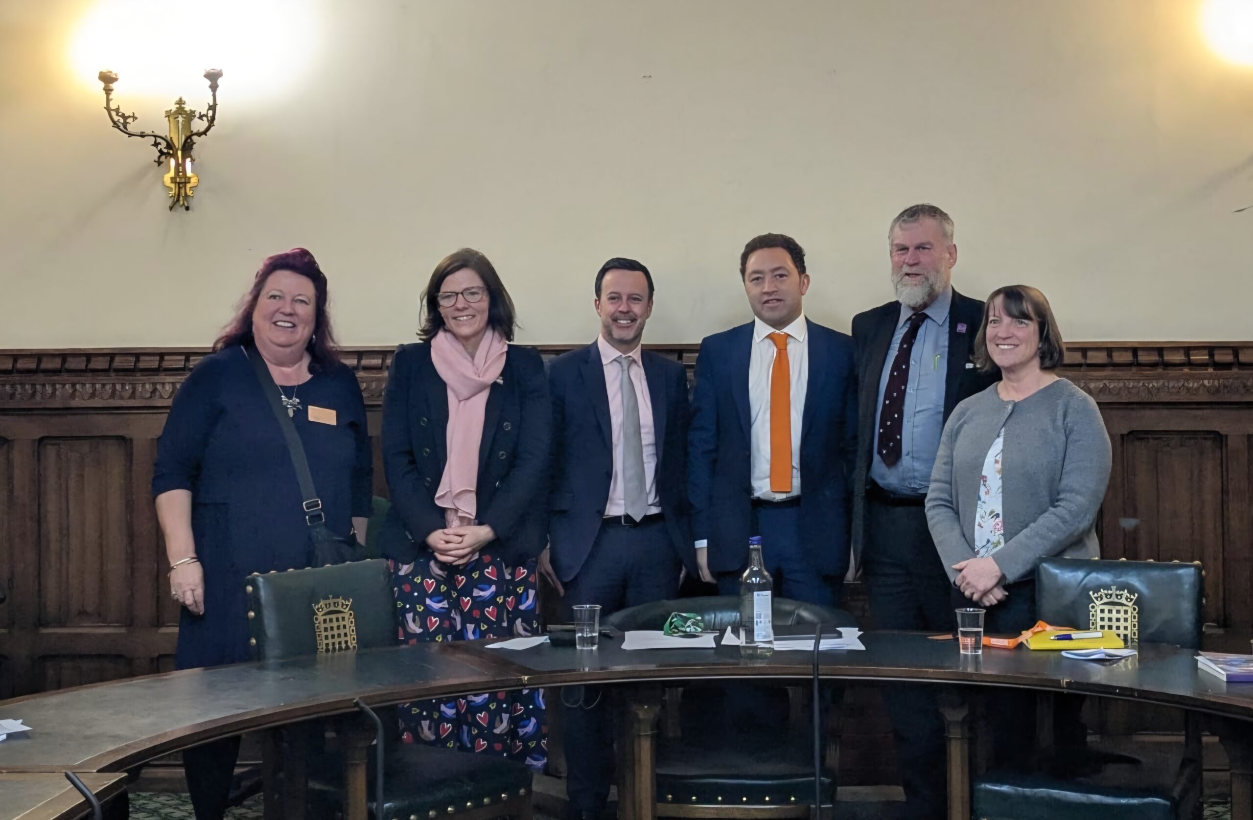 6 people standing behind a desk.