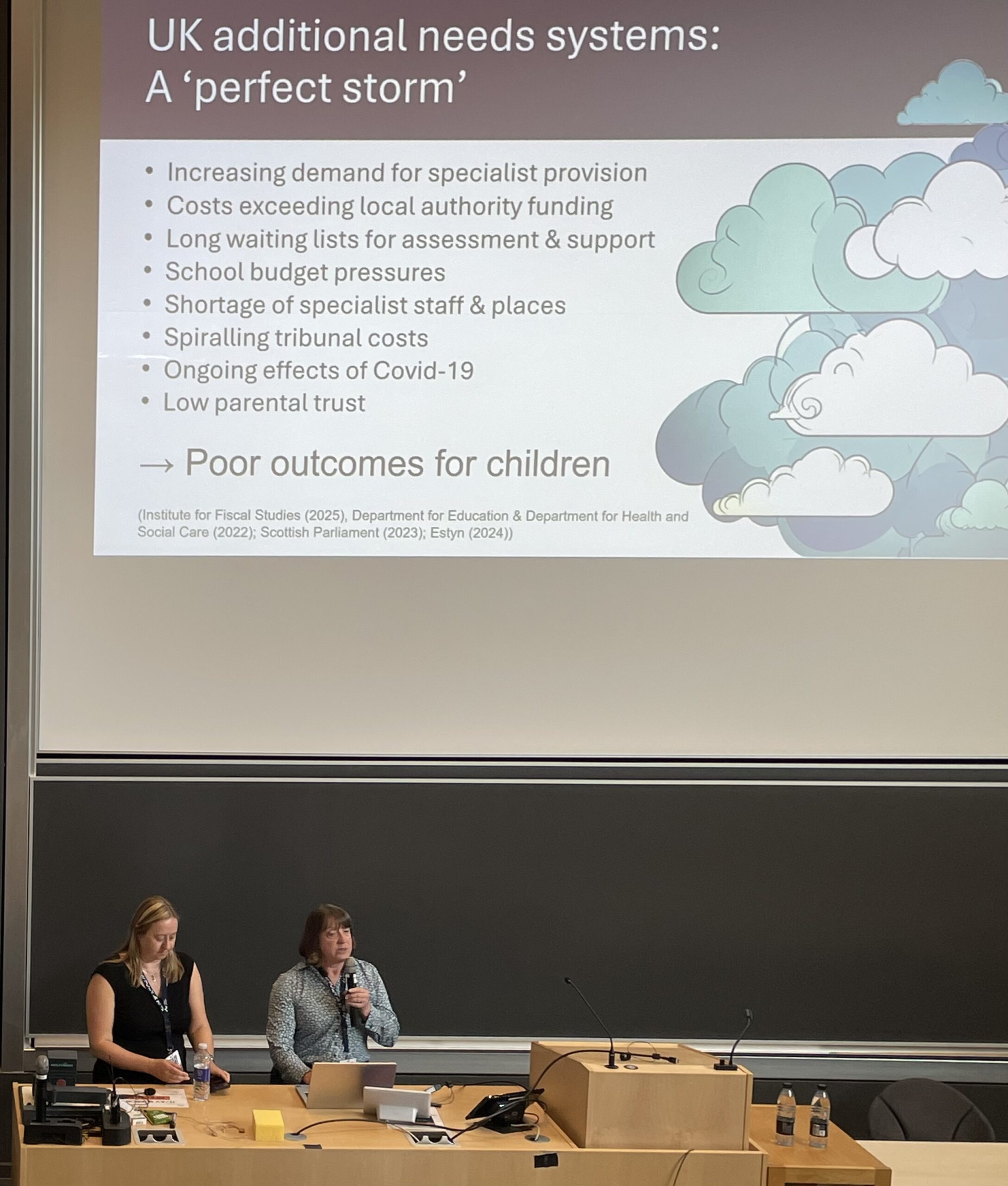 IMG_3105 Claire Lee and Alison Cotton present research at conference. A slide projected on a screen behind them depicts 'perfect storm' in UK additional needs provision.